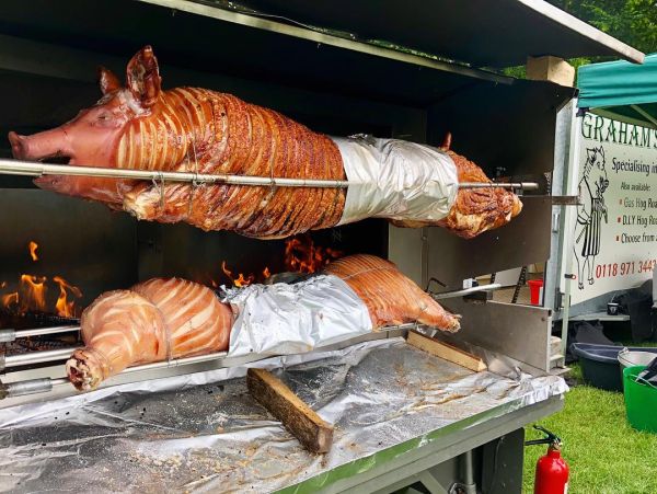 two pigs on a wood fire spit