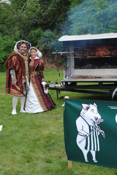 people in costumes next to a Hog Roast Machine